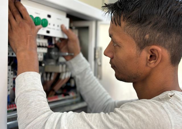 Elektricien die het deksel van een open schakelkast terugzet